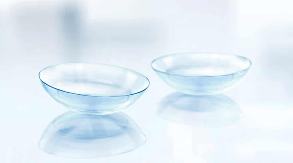 Two contact lenses on a sterile white countertop in a clinical environment with a narrow depth of field.