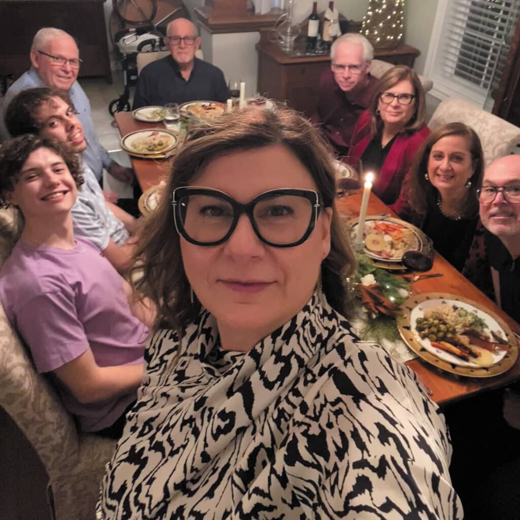 Christine Zeggil selfie with a dinner party behind her.