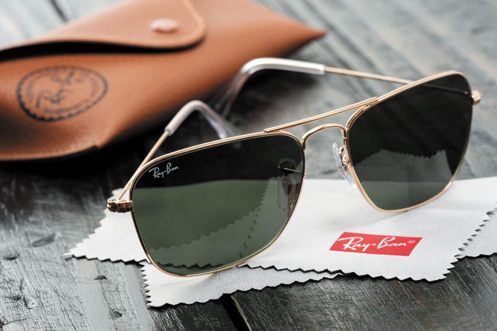 A pair of Ray-Ban sunglasses on top of a Ray-Ban micro-fibre cloth. A Ray-Ban leather glasses cases is behind, out of focus.